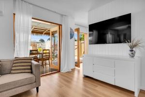 Una sala de estar con un sofá y un televisor. en Bellvilla - Kingfisher 5 Bd Suite, en Merimbula