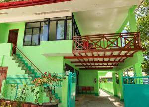 a green house with a balcony and stairs at Resort Manuela Panglao in Panglao +10 photos