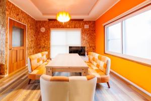 ein Esszimmer mit orangefarbenen Wänden sowie einem Tisch und Stühlen in der Unterkunft 美瑛ゆめゆめハウス in Biei