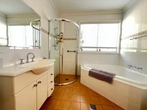 ein Badezimmer mit Badewanne, Waschbecken und Dusche in der Unterkunft Cozy Mountain Cottage in Katoomba + 21 Fotos