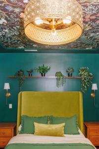 a bedroom with a bed with a yellow headboard and a chandelier at The Velvet Manor | OTR Deck+Parking, Sleeps 8! in Over-The-Rhine