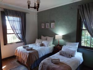 a bedroom with two beds and two windows at De Mist Graskop in Graskop