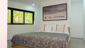 a bedroom with a bed with white walls and windows at Teras by Tamora in Badung