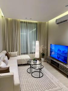 a living room with a white couch and a flat screen tv at شقة أنيقة بغرفتين نوم وصالة in Al Khobar +14 photos