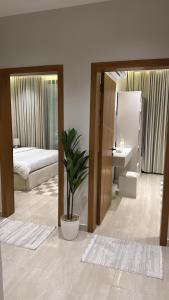 a bedroom with a bed and a potted plant at شقة أنيقة بغرفتين نوم وصالة in Al Khobar