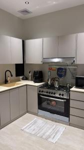 a kitchen with a stove and white cabinets at شقة أنيقة بغرفتين نوم وصالة in Al Khobar +9 photos