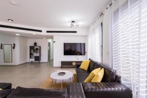 a living room with a black leather couch and yellow pillows at זוהר במדבר ים המלח in Neve Zohar