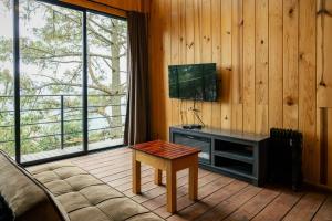a room with a tv and a table and a couch at Rocabosque oaxaca in San Mateo Río Hondo
