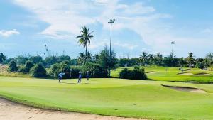 a group of people playing golf on a golf course at Phuc Thanh Luxury Hotel by THG in Danang