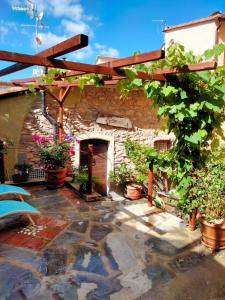 a patio with a stone building with a wooden pergola at A fenera in Dolcedo