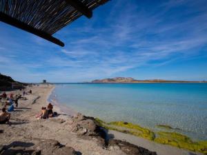 a group of people sitting on the beach at Holiday Home in Stintino near La Pelosa Beach in Stintino