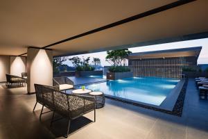 una grande piscina con sedie e un tavolo accanto di Mercure Madiun a Madiun