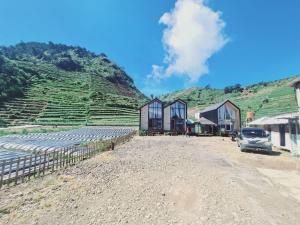 a group of houses and a truck parked in front of a hill at cabin view danau in Kejajar