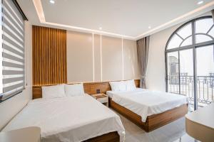 a hotel room with two beds and a window at Sunflower Hotel in Sầm Sơn