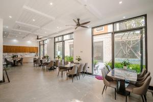 a dining room with tables and chairs and windows at Sunflower Hotel in Sầm Sơn
