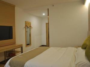 a bedroom with a bed and a flat screen tv at GreenTree Inn Heze Changcheng Road Tianhua E-commerce Logistics Park Express Hotel in Heze