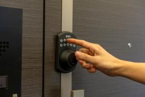a persons hand pressing a door button in an elevator at The Apartment Hotel 代々木1 in Tokyo