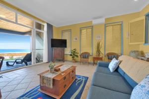 a living room with a blue couch and a view of the ocean at Beachfront Bliss for Two l Nova Escapes in The Entrance