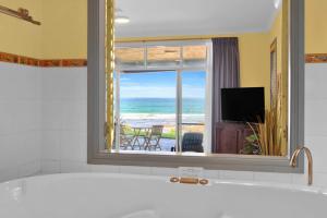 a bathroom with a window with a view of the ocean at Beachfront Bliss for Two l Nova Escapes in The Entrance