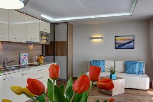 a kitchen and a living room with red tulips at Marina Jastarnia Apartamenty in Jastarnia