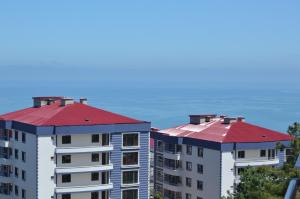 トラブゾンにあるEvim Trabzon Apartmentの海を背景にした赤い屋根の建物2棟