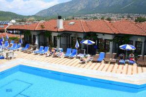 a group of people sitting on a deck by a pool at Hisar Holiday Club in Oludeniz