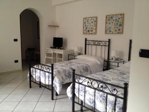 a bedroom with two beds and a desk and a television at Akron B&B in SantʼAlessio Siculo