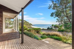 a wooden porch with a view of the ocean at Chinamans at Hyams Beach in Hyams Beach
