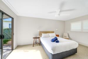 a bedroom with a bed and a sliding glass door at Chinamans at Hyams Beach in Hyams Beach