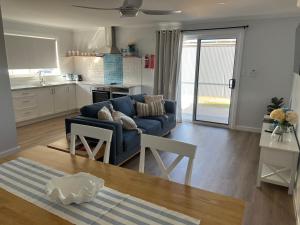 a living room with a blue couch and a kitchen at Arno Bay Tourist Accommodation in Arno Bay