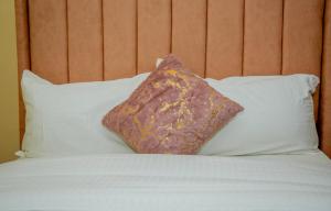 a pillow sitting on top of a bed with white pillows at Stylish Mauve Studio with free WI-FI in Nanyuki +8 photos