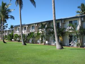 a building with palm trees in front of it at Cardwell Beachcomber Motel & Tourist Park in Cardwell
