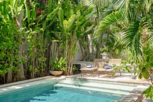 a swimming pool in a garden with chairs and trees at Ocean Luxury Villas - Seminyak in Seminyak