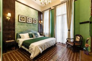 a bedroom with green walls and a bed and a chair at Origin Antique House and Hotel in Guangzhou