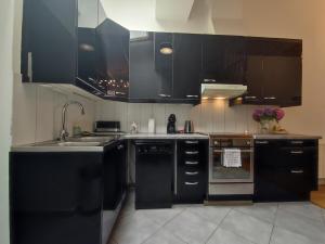 a kitchen with black cabinets and a sink at TOK TOK VH Maison 1 Chambre, proche gare et centre de Seclin in Seclin