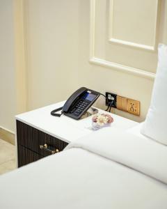 a desk with a phone on top of a bed at Faletti's Express Hotel Airport Lahore in Lahore
