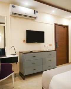 a bedroom with a dresser with a tv on the wall at Faletti's Express Hotel Airport Lahore in Lahore