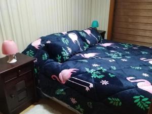 uma cama com um edredão azul com flamingos cor-de-rosa em Hostal Aurora Coronel em Concepción mais 15 fotografias