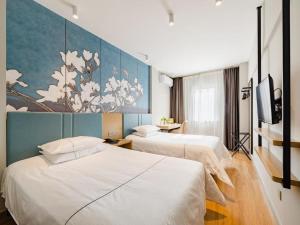 ein Hotelzimmer mit zwei Betten und einem Gemälde an der Wand in der Unterkunft Jinjiang Inn Shenyang Xinggong North Street METRO in Shenyang + 203 Fotos