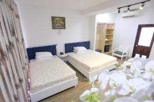 two beds in a room with white walls and flowers at Rain Bow Hotel in Ho Chi Minh City