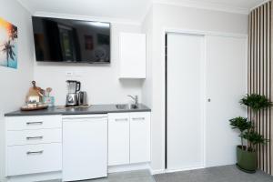 a kitchen with white cabinets and a sink at Banana Bungalow Studio in Raglan