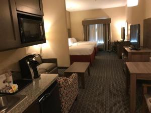 a hotel room with a bedroom with a bed and a television at Holiday Inn Express & Suites Fredericksburg By IHG in Fredericksburg