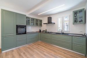 a large kitchen with green cabinets and wooden floors at Ognissanti Holiday House in Ragusa