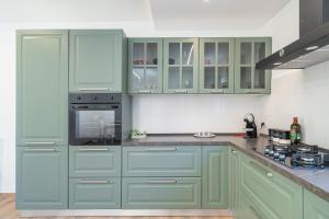 a kitchen with green cabinets and a stove at Ognissanti Holiday House in Ragusa +28 photos