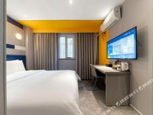 a hotel room with a bed and a desk and a tv at 7 Days Inn Chongqing Nanping Wanda Plaza Exhibition Center in Chongqing