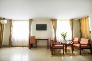 un soggiorno con tavolo, sedie e TV di Luxe Hotel a Dong Hoi