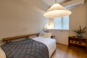 東京にあるThe Apartment Hotel 恵比寿1のベッドルーム(ベッド1台、大型ペンダントライト付)