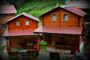 two wooden houses with red roofs and green chairs at Ayder Bulut Dağevi Bungalow in Ayder Yaylasi