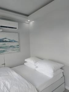 a white bedroom with a bed with white pillows at Urban Oasis with Skyline View in Manila