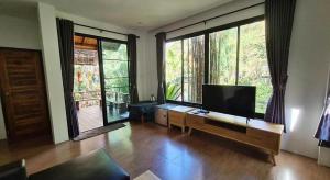 a living room with a flat screen tv and large windows at NantraKiri in Ban Na Kham